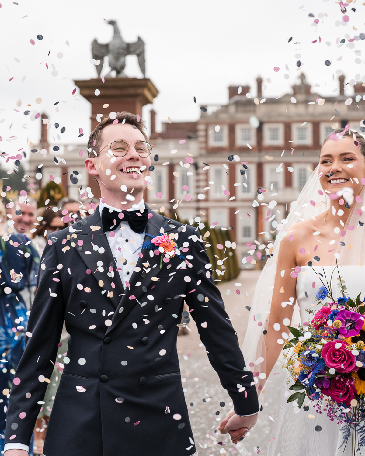 Newlyweds walking through a shower of confetti, photographed by Kevin Joseph